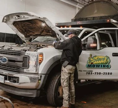 Mechanic inspecting engine of lawn service truck.