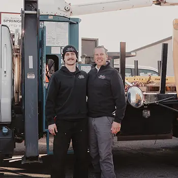 Two workers standing next to a utility truck.